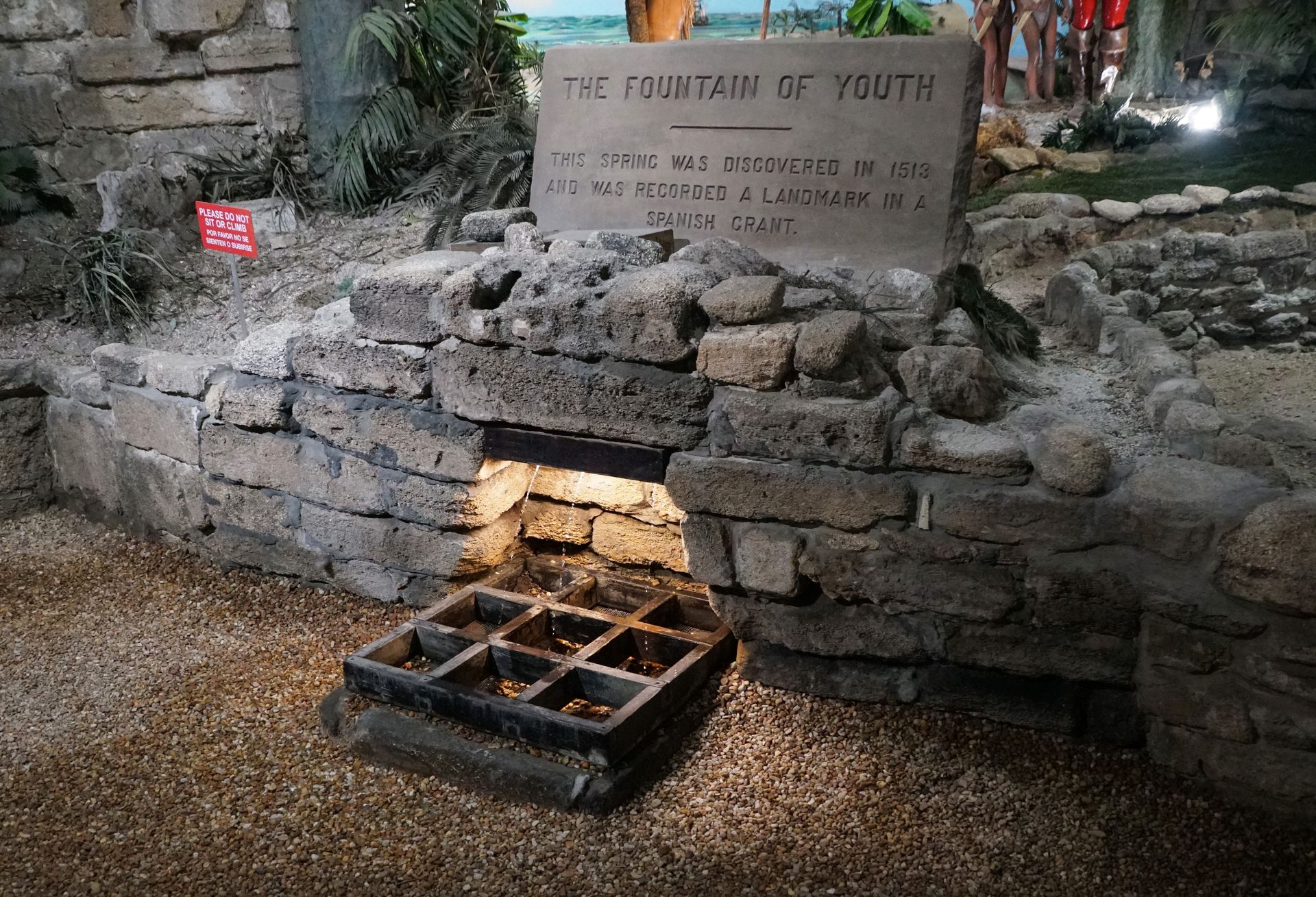 A stone wall with a sign that says the fountain of youth