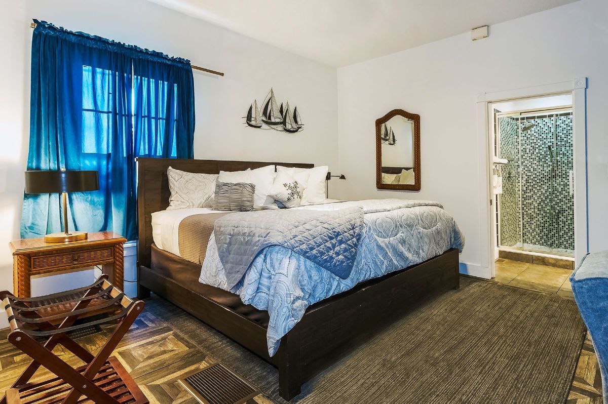 a bedroom with a king size bed , nightstand , mirror and blue curtains .