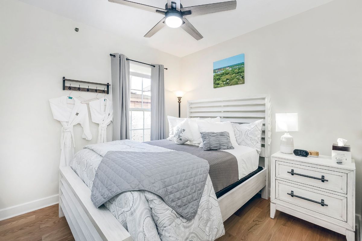 a bedroom with a bed , nightstand , dresser and ceiling fan .