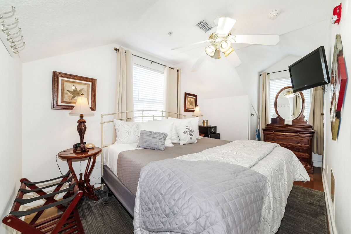 a bedroom with a king size bed , dresser , television and ceiling fan .