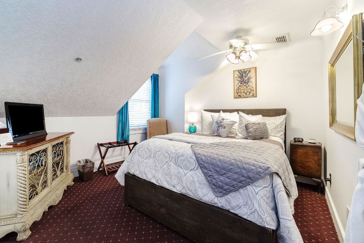 a bedroom with a bed , dresser , television and mirror .