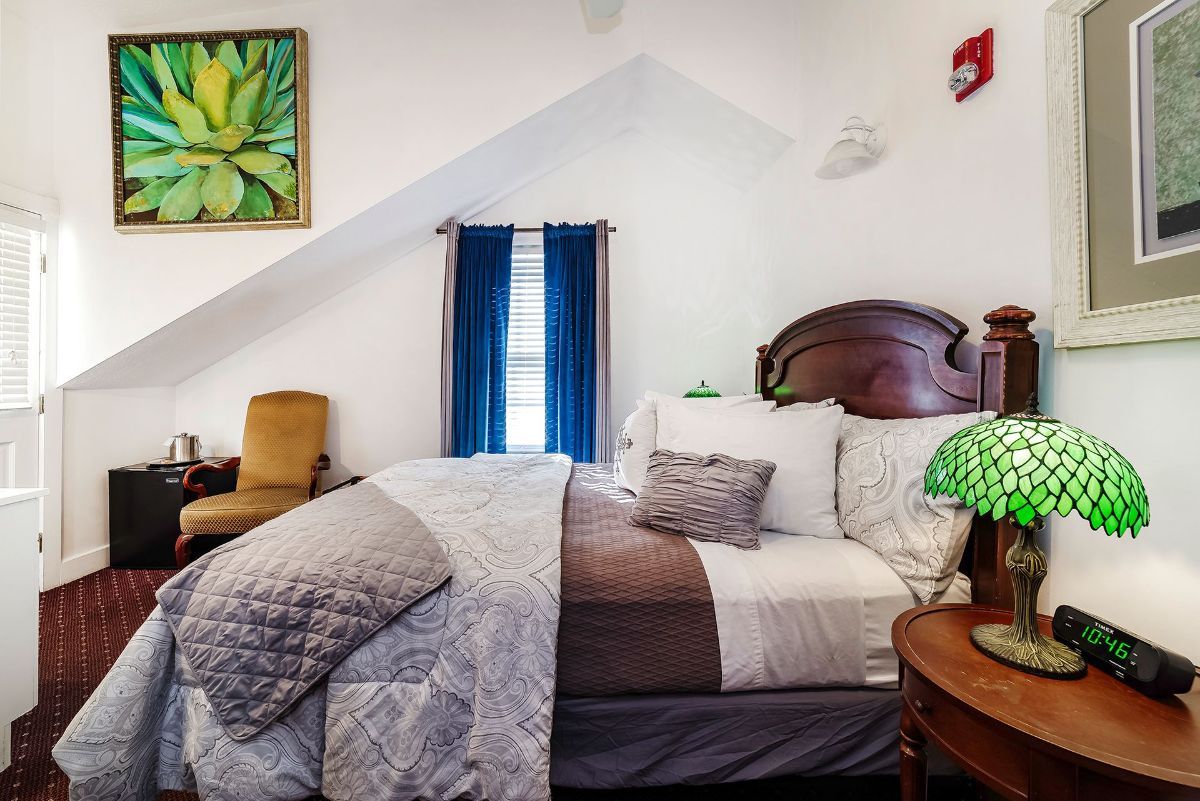 a bedroom with a bed , lamp , chair and painting on the wall .