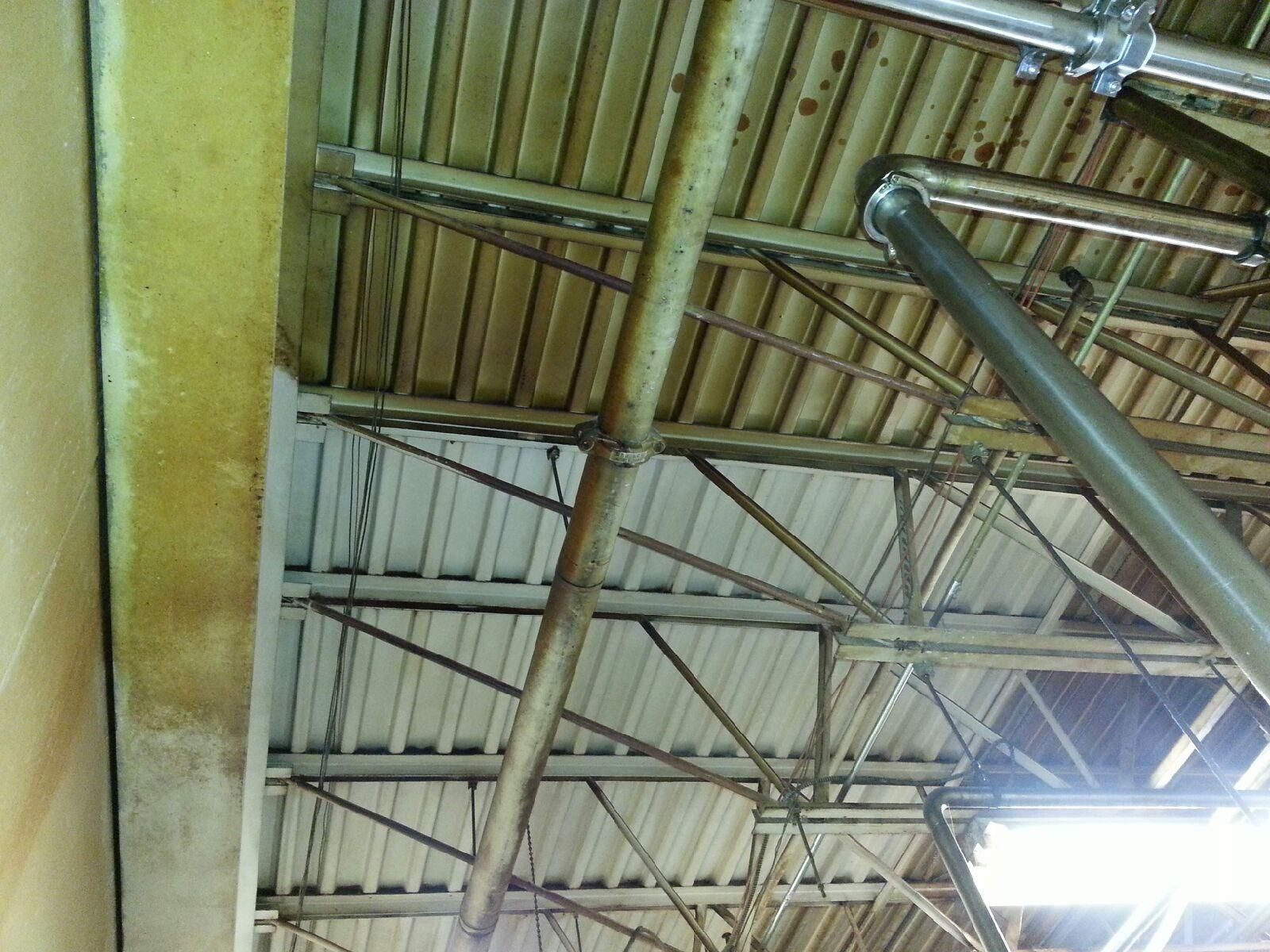 Metal ceiling with pipes and support beams; yellow wall on the left.