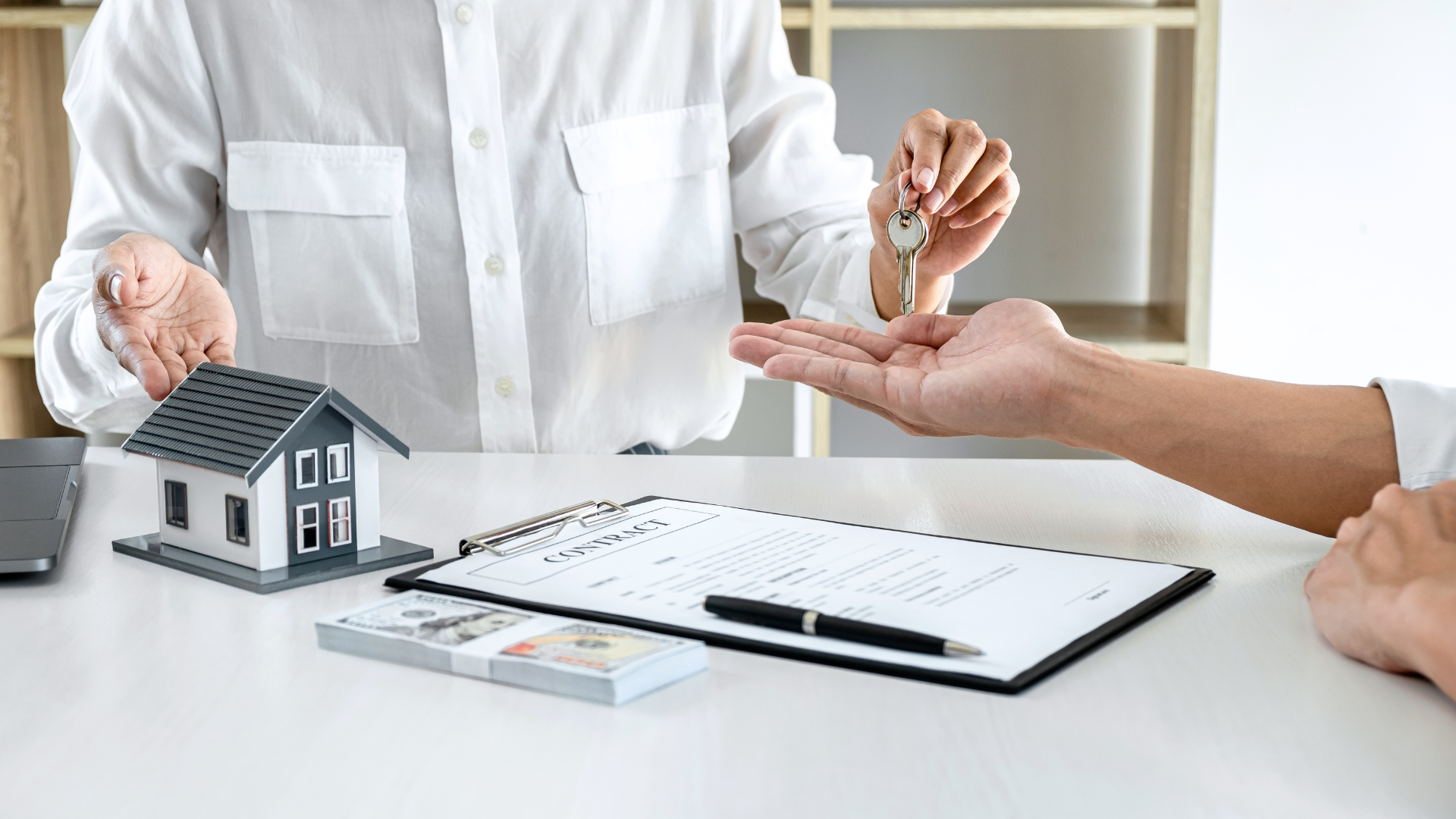 A man is giving a house key to a woman.