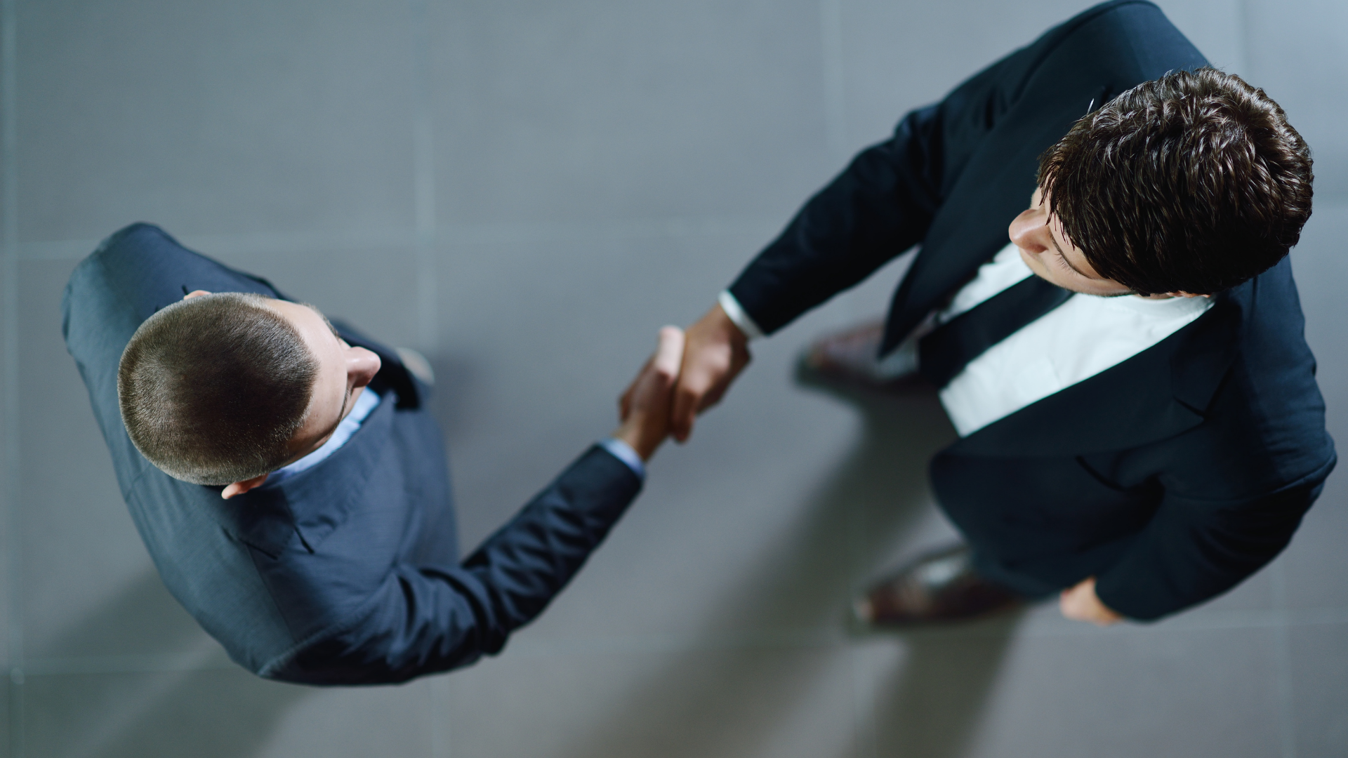 A man in a suit and tie is shaking hands with another man in a suit and tie.