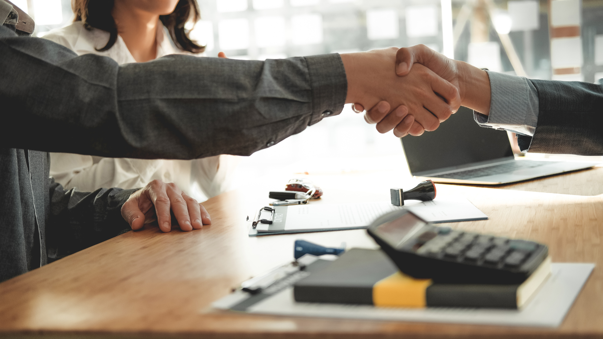 A man and a woman are shaking hands over a table.