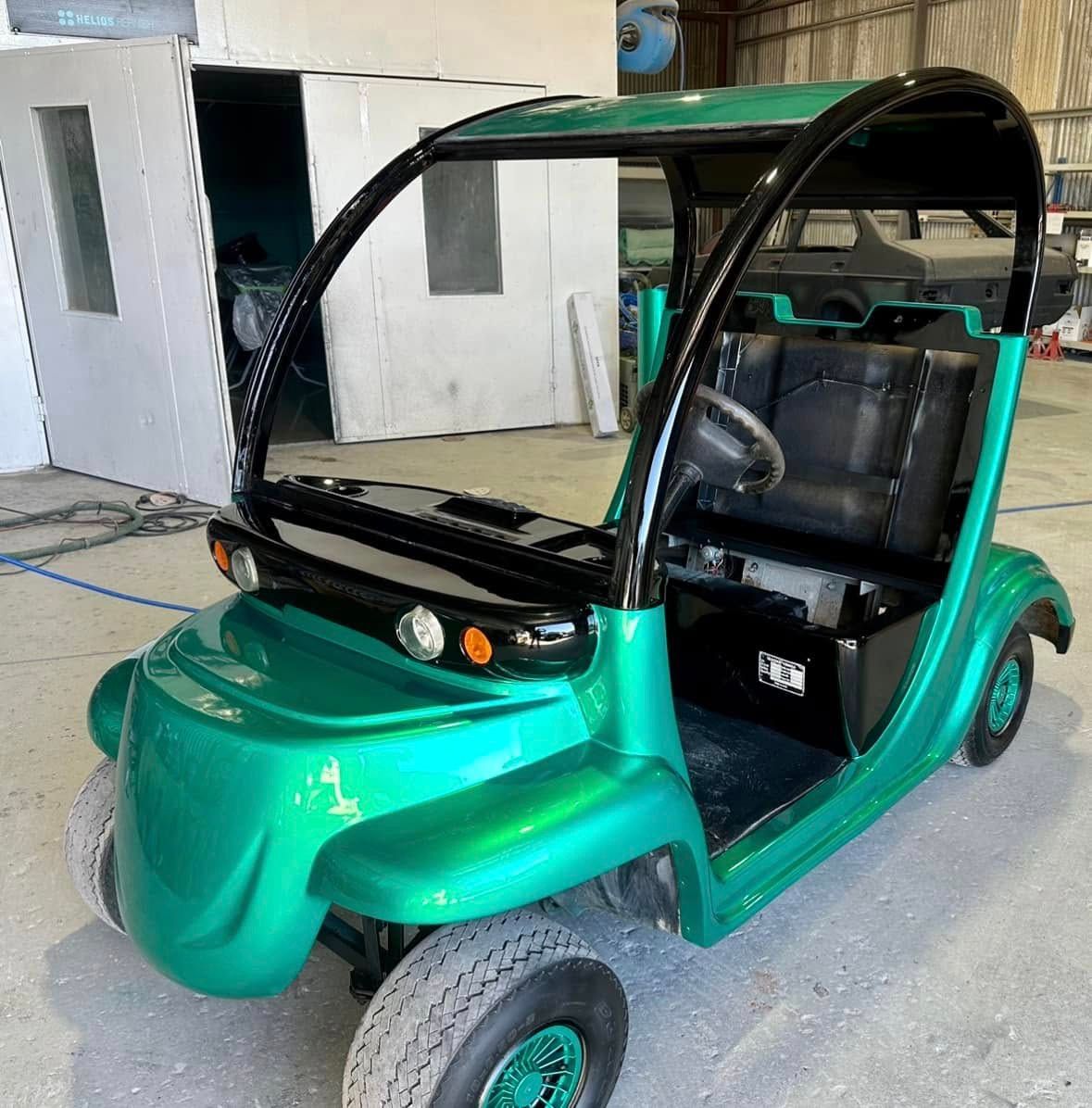 A green golf cart is parked in a garage.