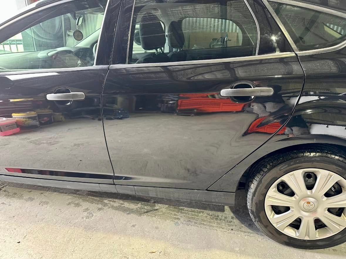 A black car is parked in a garage with the door open.