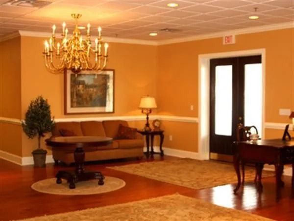 A room with orange walls, brown furniture, a chandelier, and double doors.
