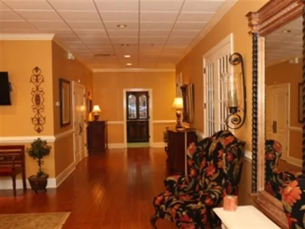 Hallway with wood floors, yellow walls, and decorative furniture and mirror.