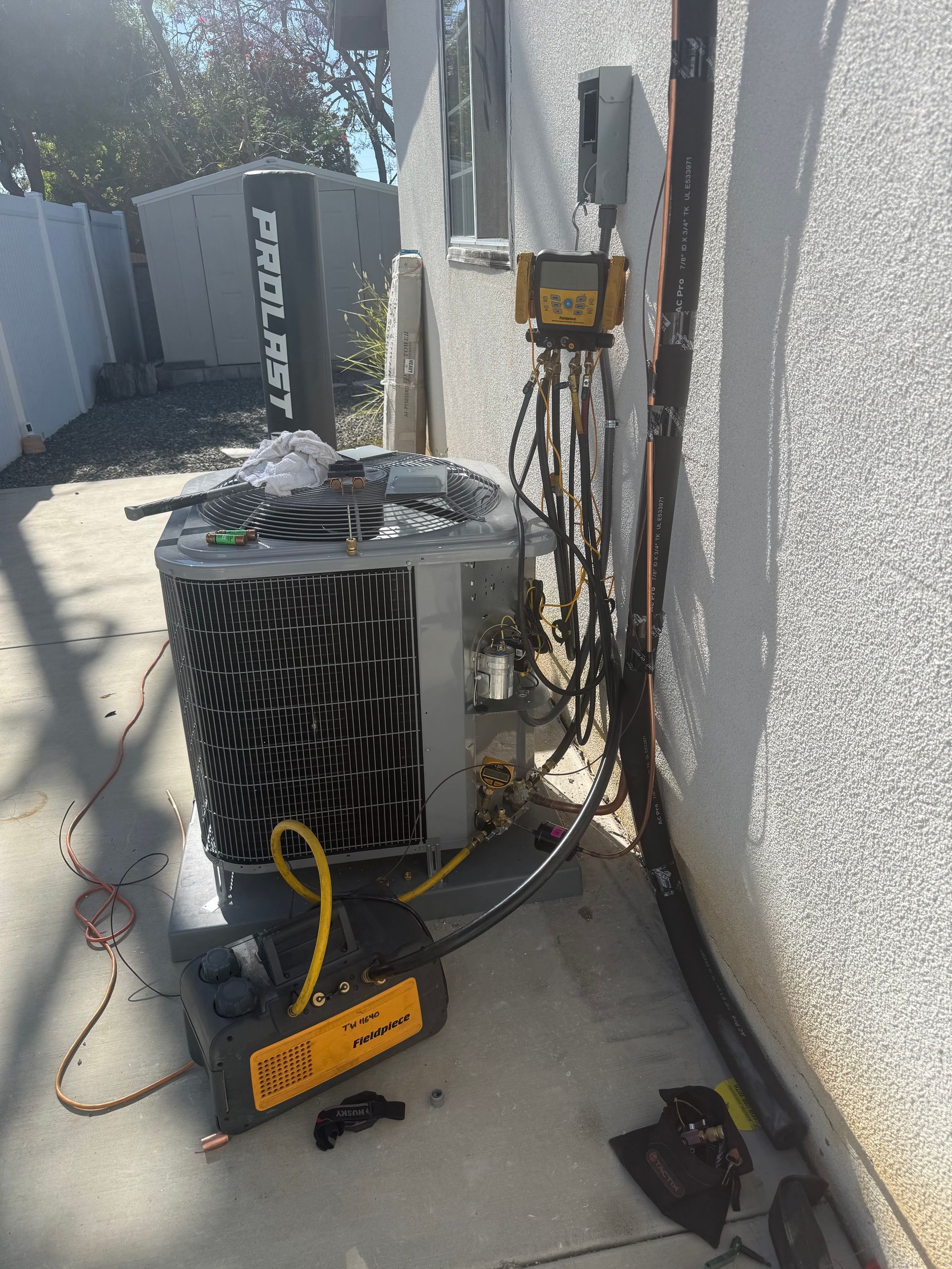 HVAC technician repairing outdoor AC unit beside a suburban house