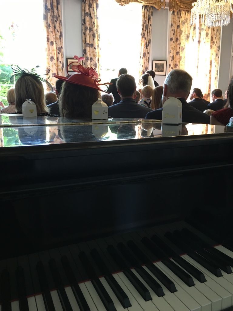 A grand piano with a closed lid in the corner of a wedding ceremony
