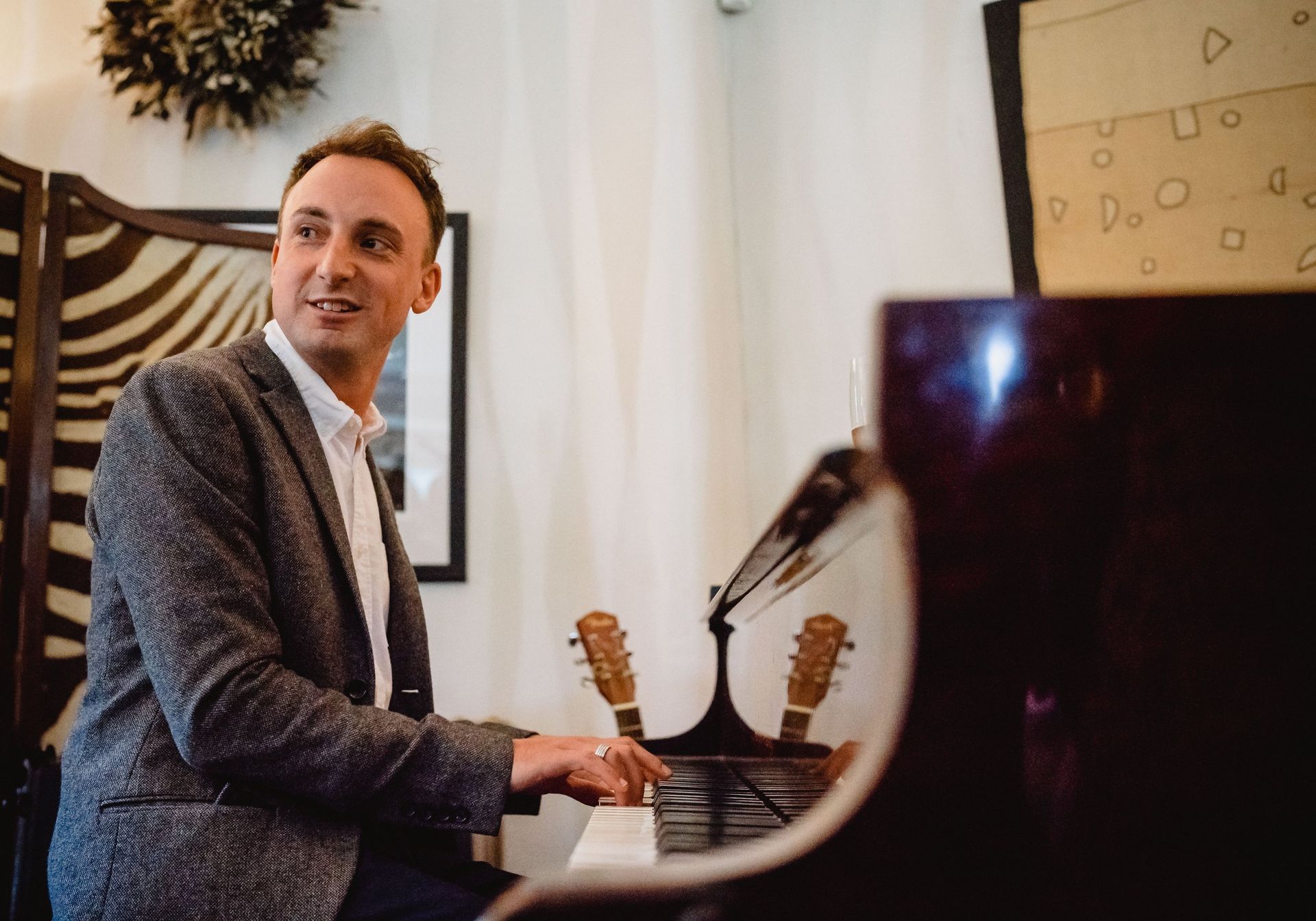 A man in a suit is playing a piano in a room.