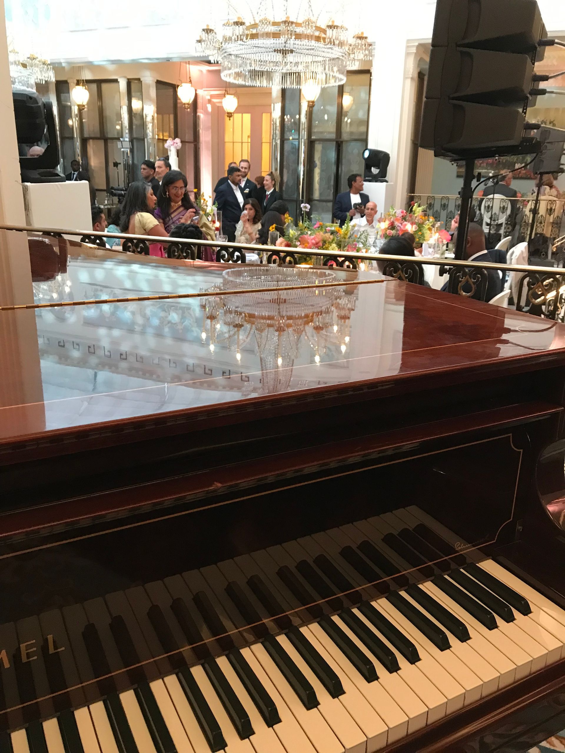 A brown grand piano in a smart London hotel with a chandelier