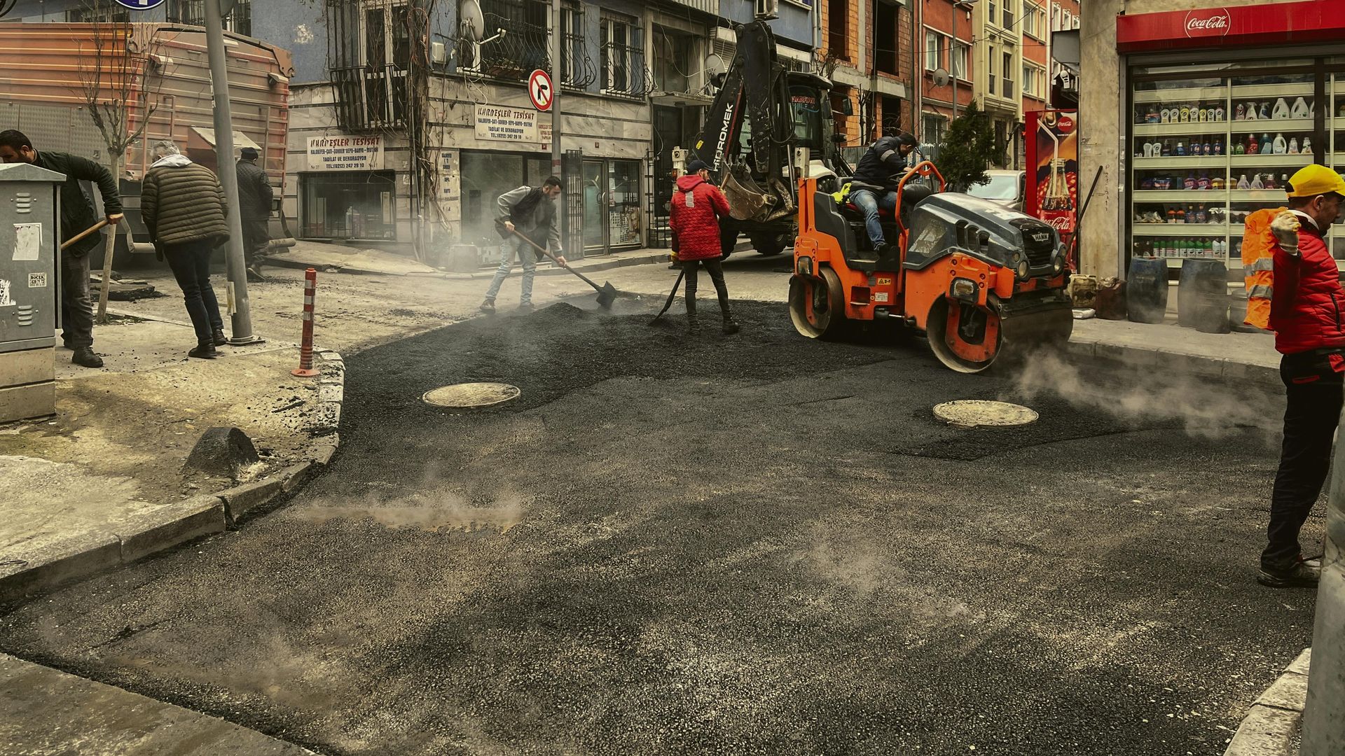 A group of construction workers are working on a street.