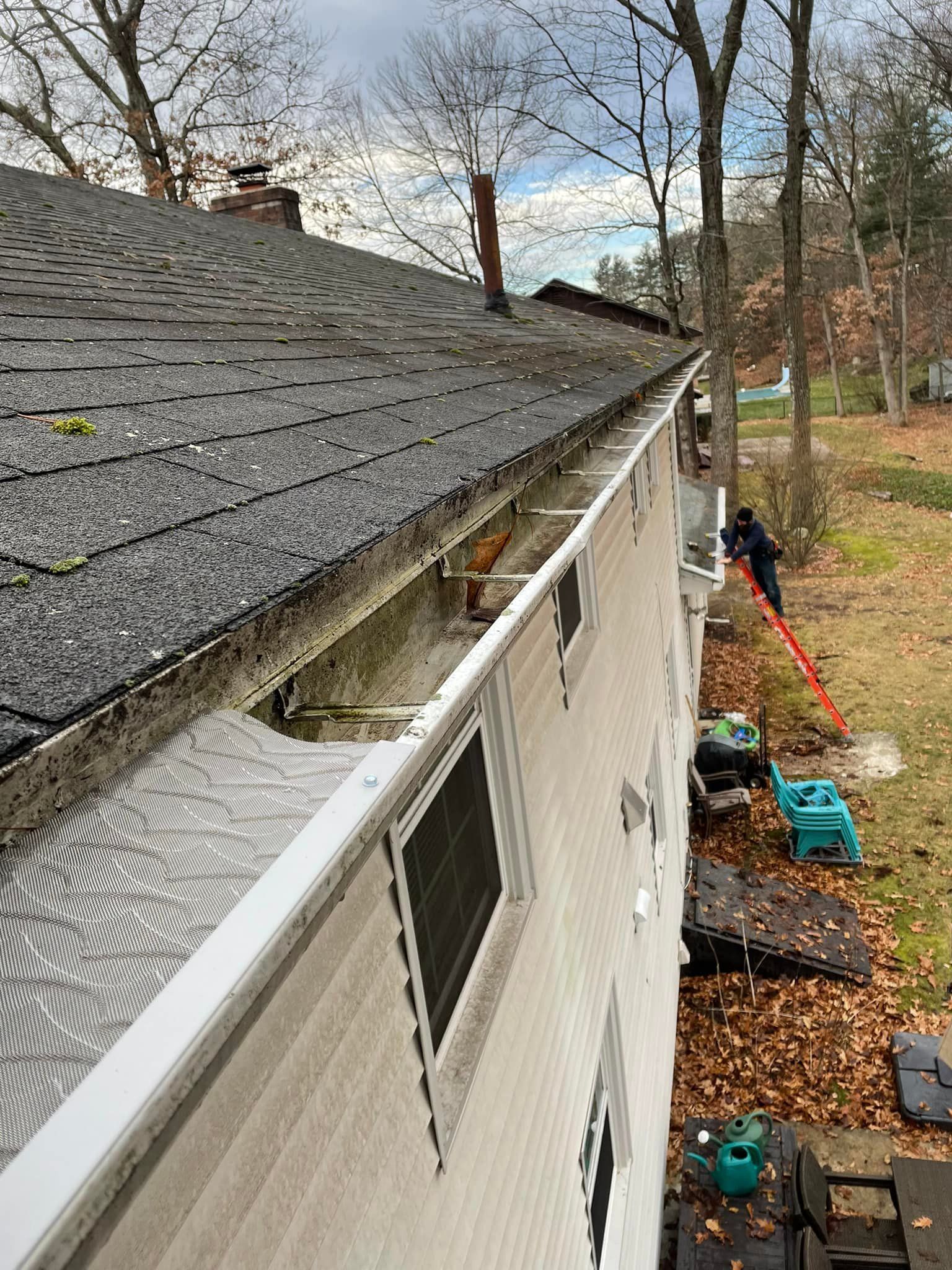 A person is cleaning a gutter on the side of a house.