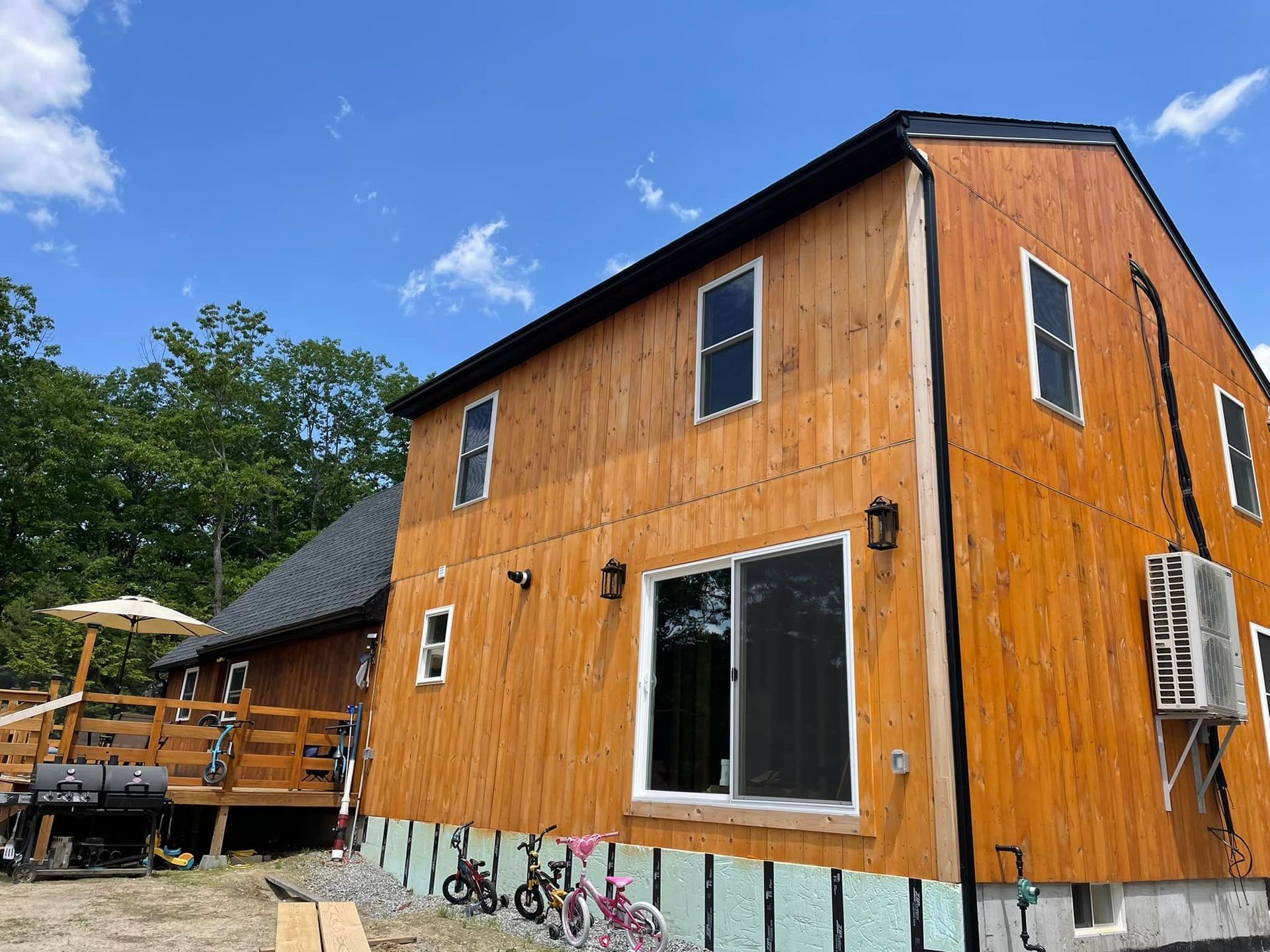 A large wooden house with a deck and bikes in front of it.