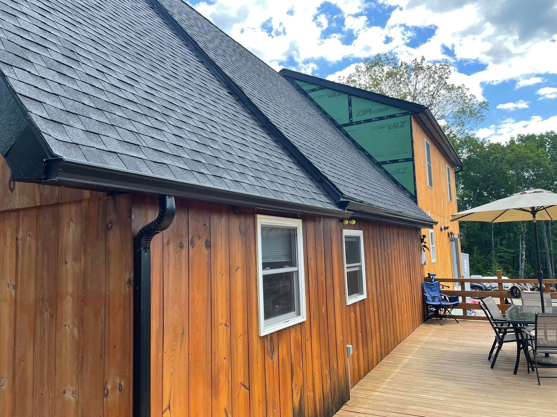A wooden house with a deck and umbrella in front of it.