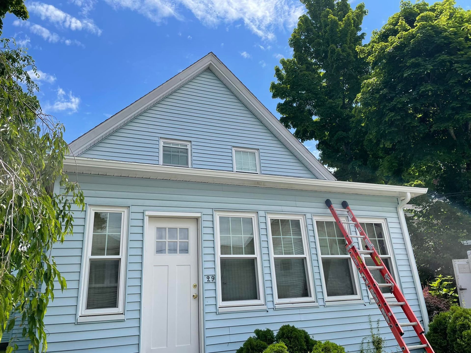 A blue house with a red ladder in front of it.