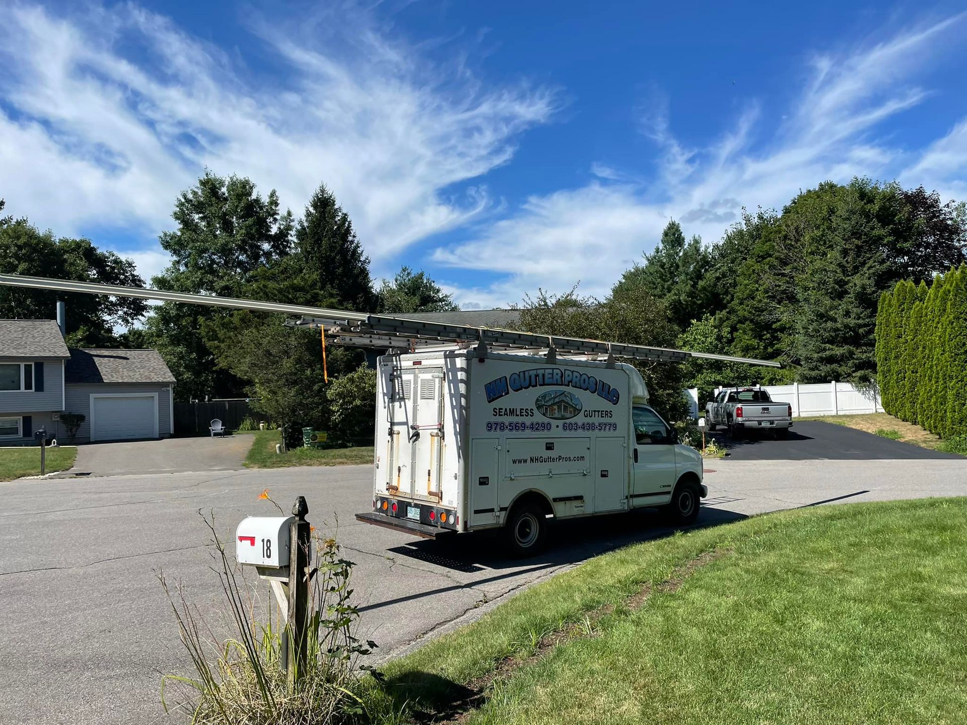 A white van is parked on the side of the road in front of a house.