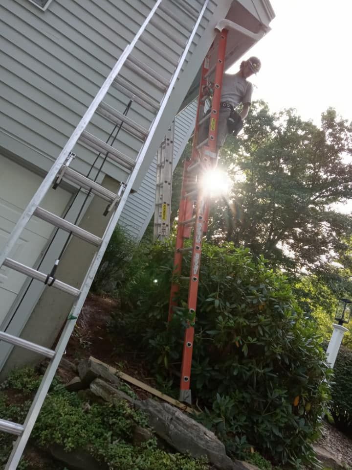 A man is standing on a ladder on the side of a house.