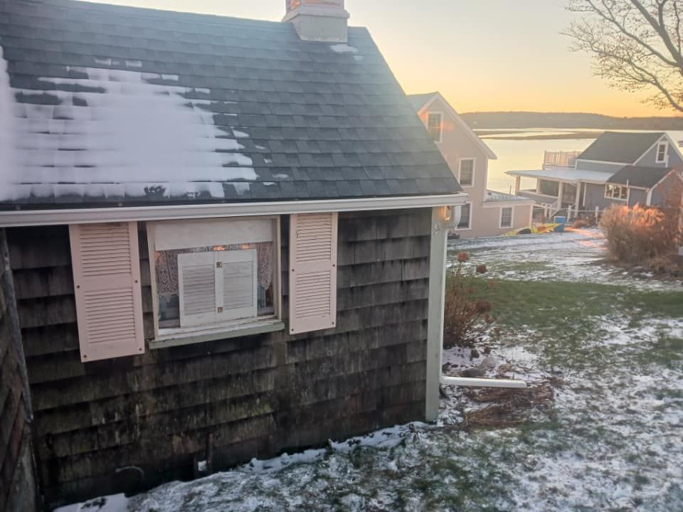 A small house with snow on the roof and a window