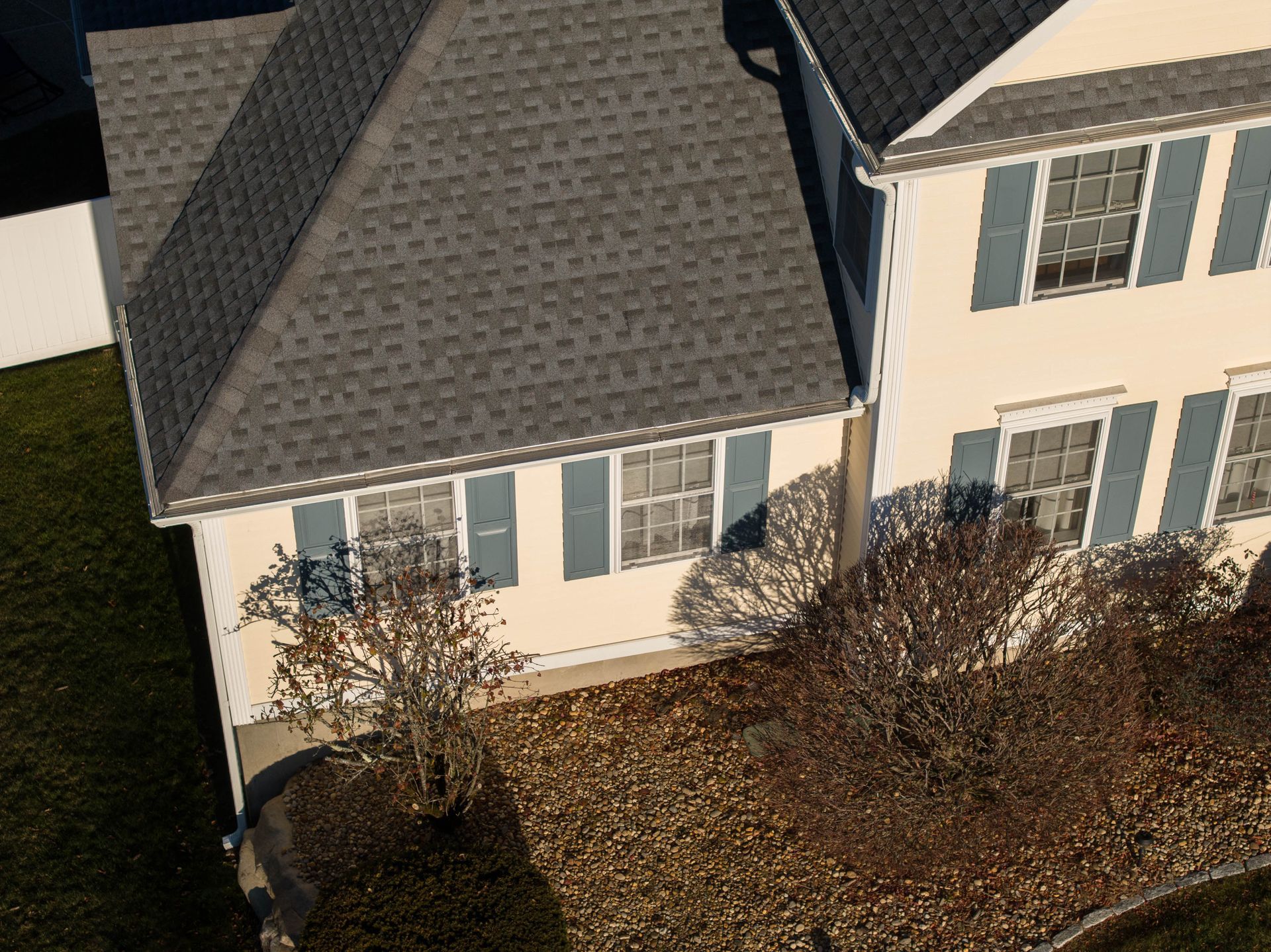 An aerial view of a house with a gray roof and white shutters.