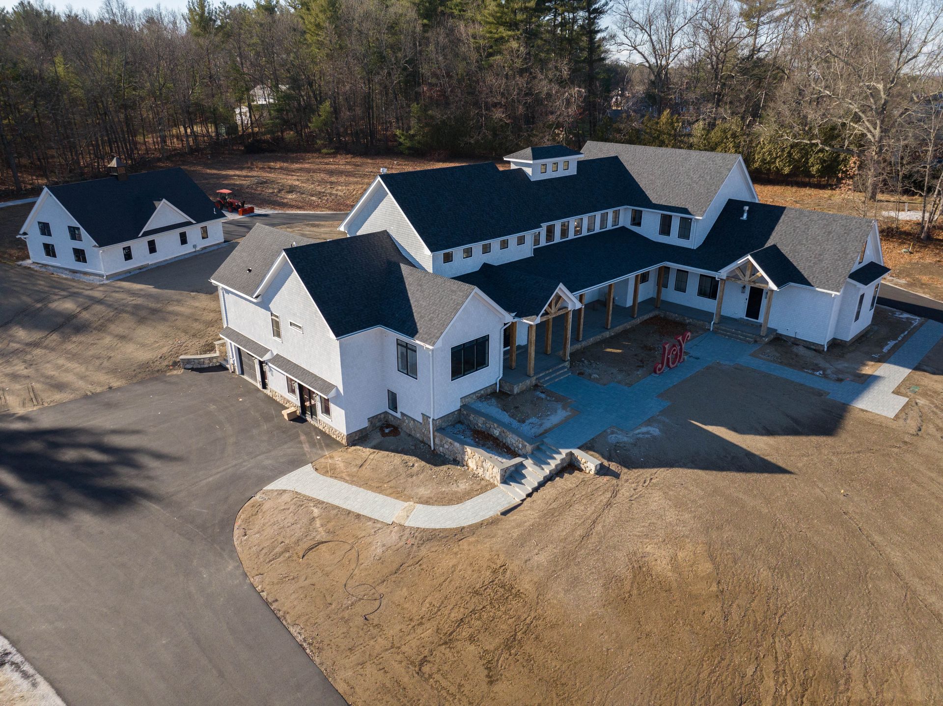 An aerial view of a large white house with black roofs surrounded by trees.