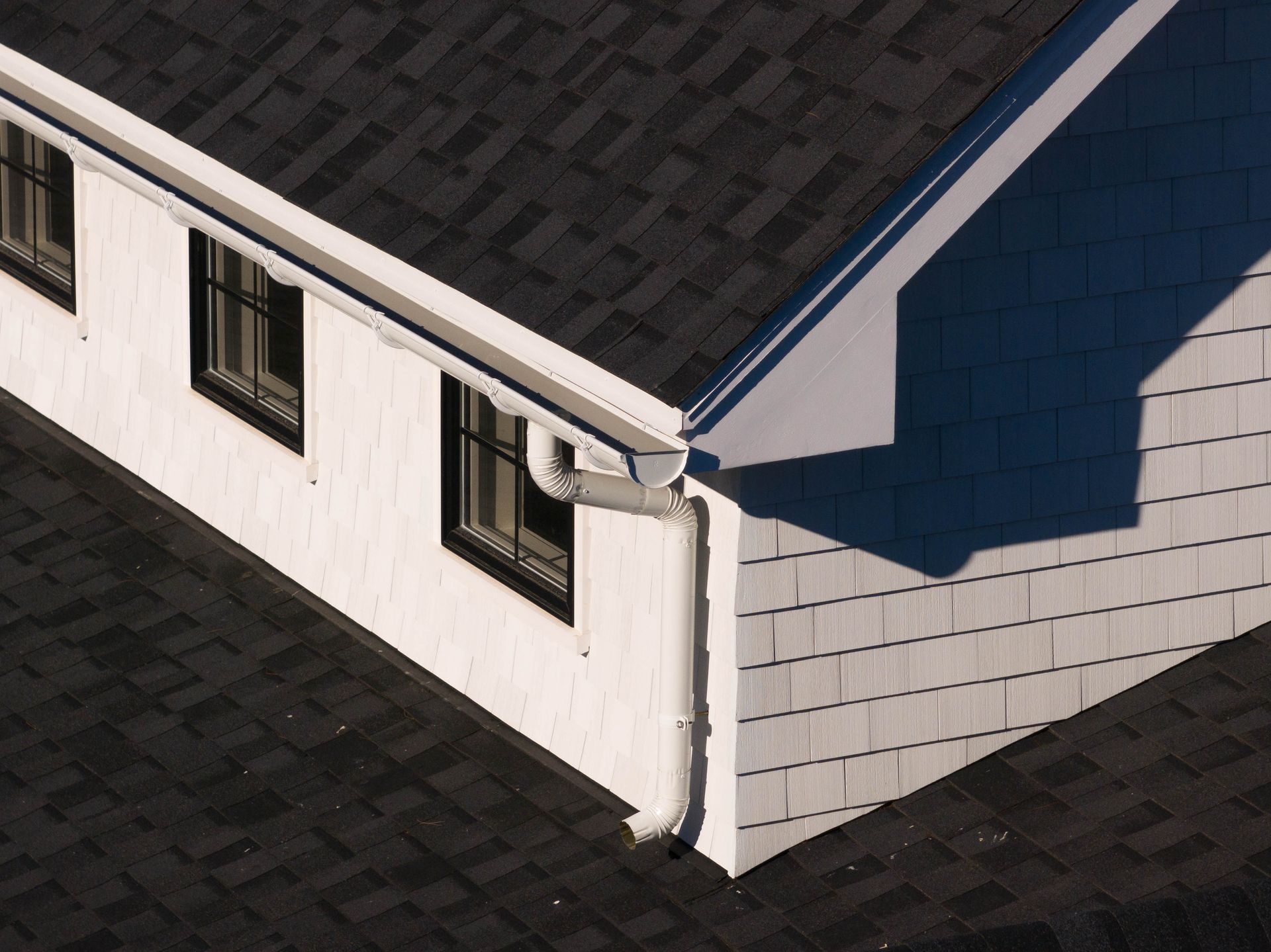 An aerial view of a white house with a black roof