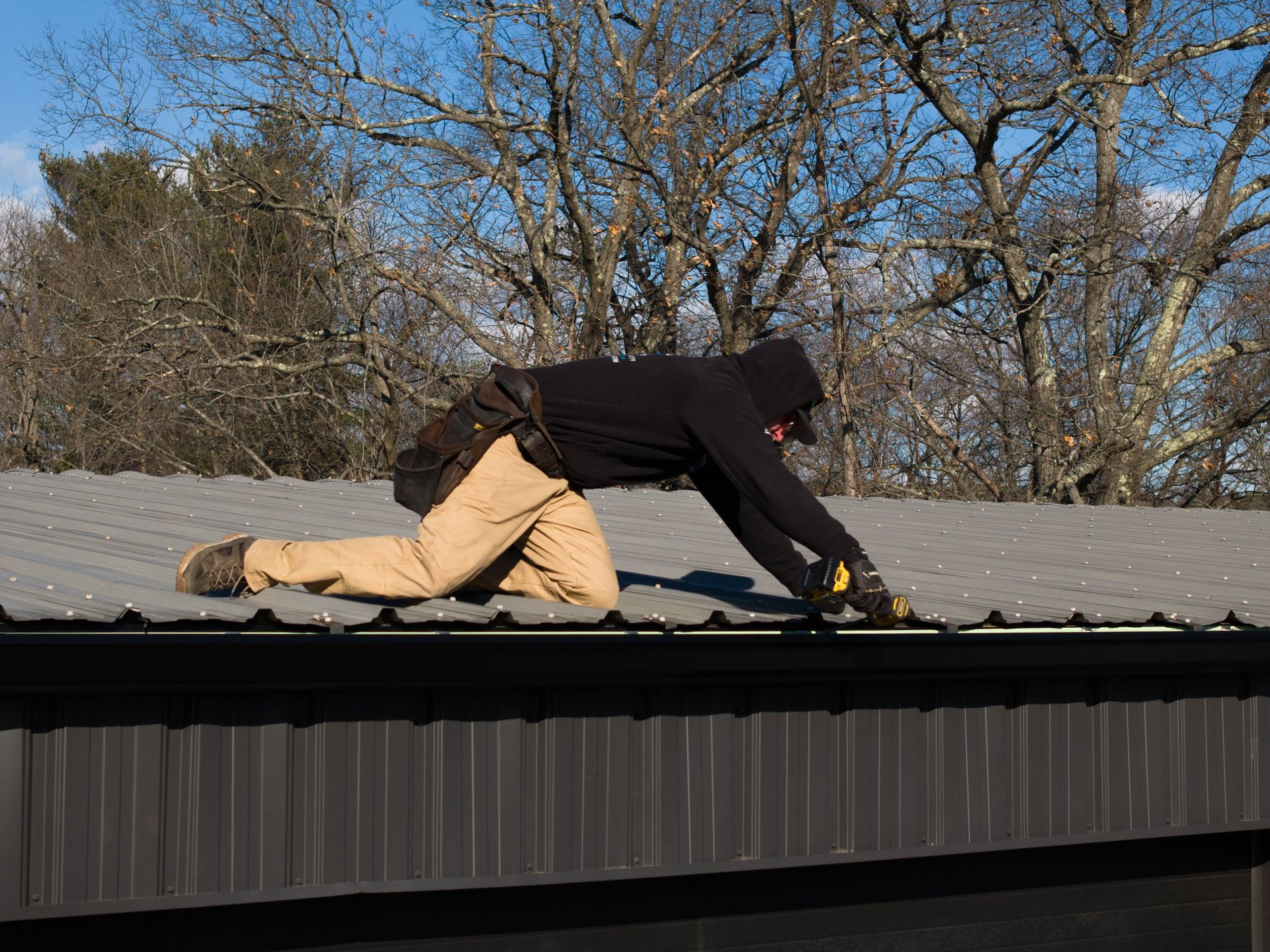 A man is kneeling on the roof of a building.