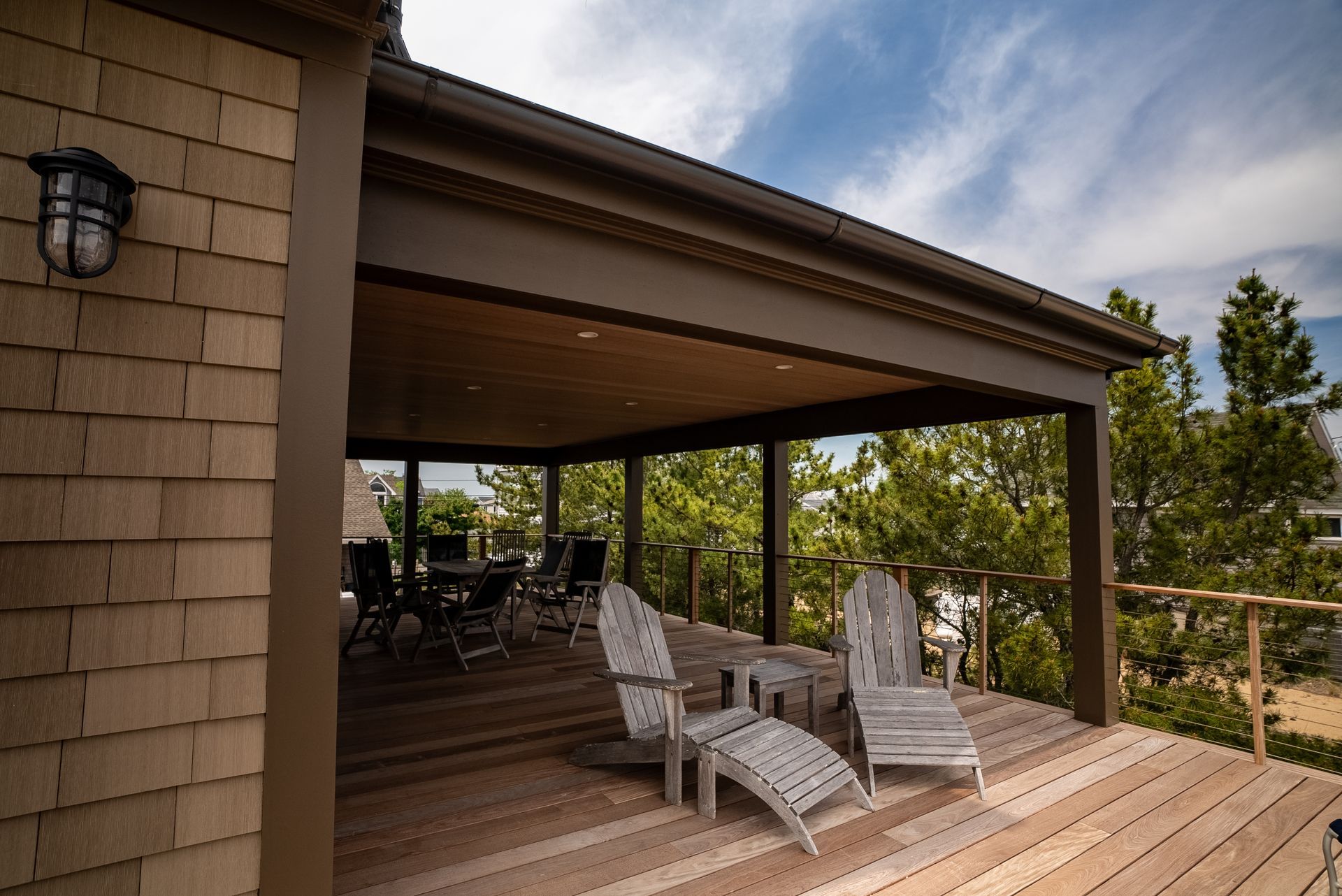 Covered wooden porch with two wicker chairs overlooking a wooded landscape