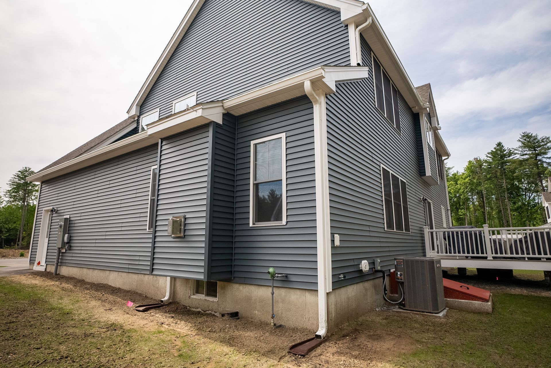 Gray house with white trim and a raised porch, viewed from the side in a grassy yard