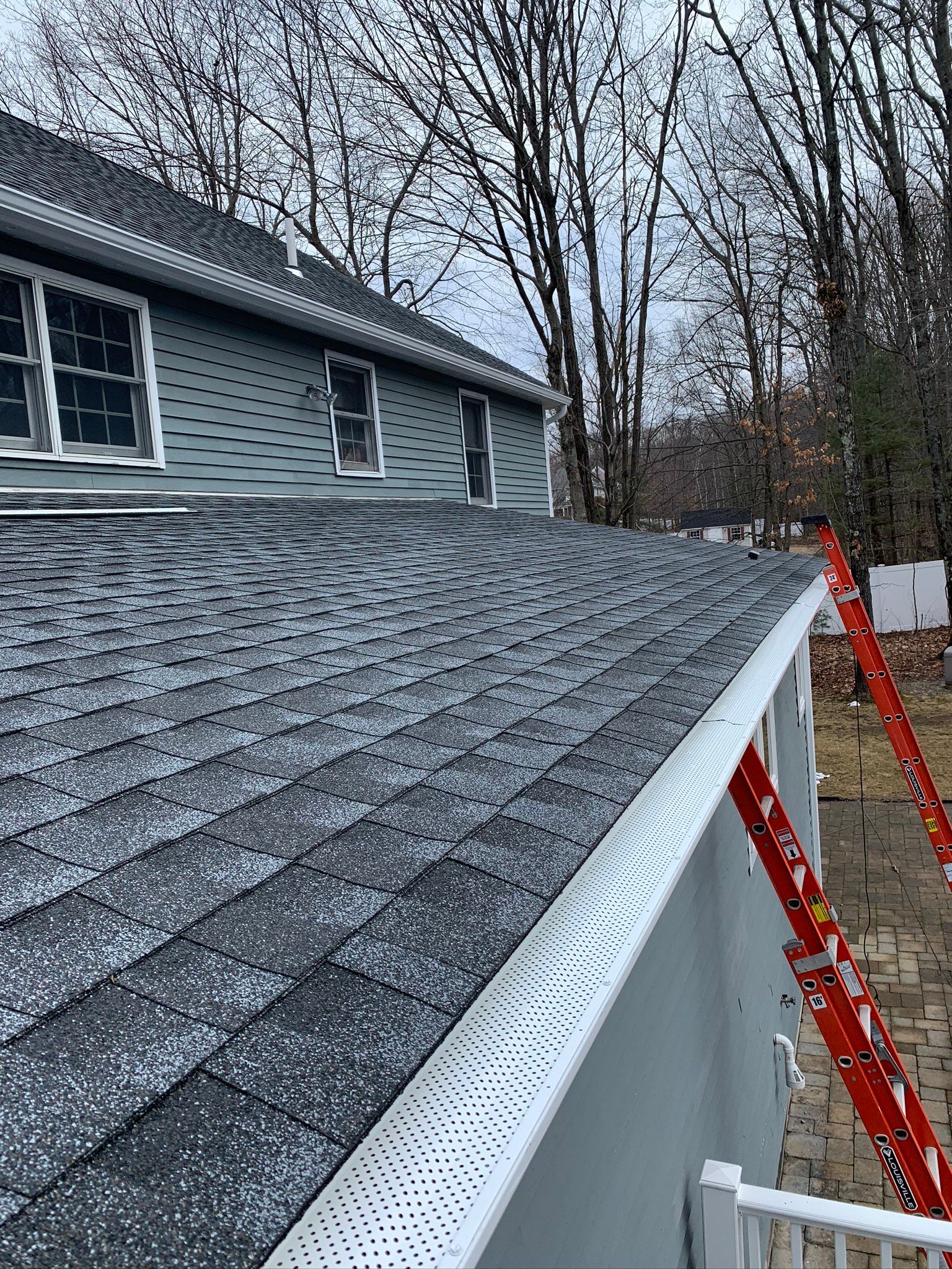A ladder is sitting on the side of a house next to a roof.