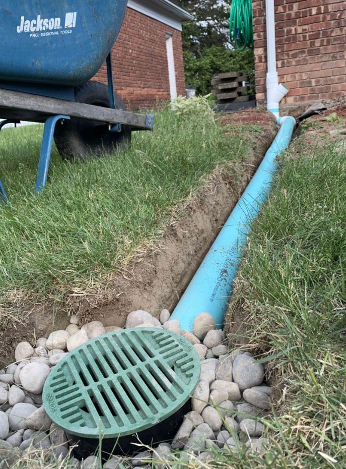 A green drain cover is sitting next to a blue pipe.