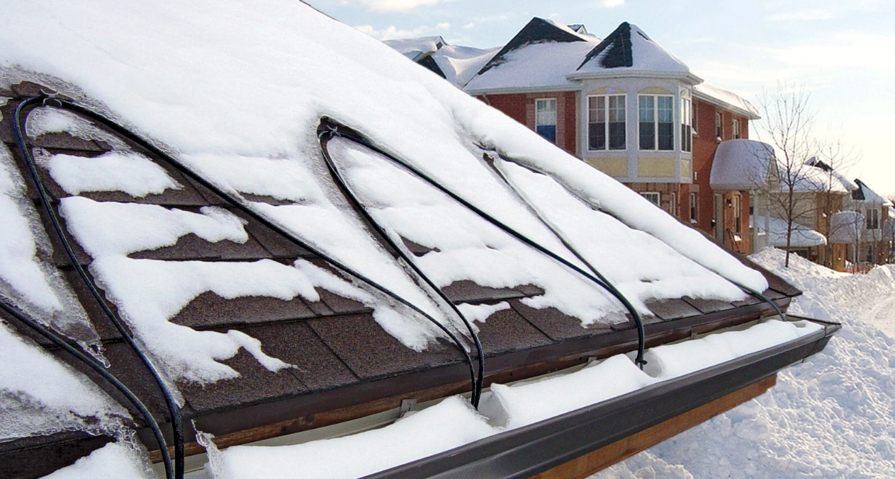 A man is standing on the roof of a house with a gutter.