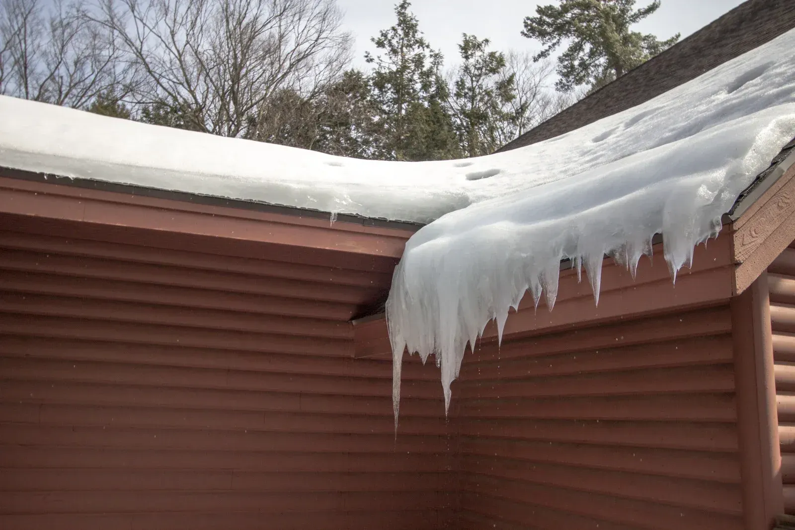 A man is standing on the roof of a house with a gutter.