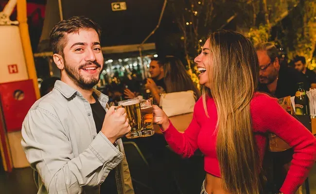 Um homem e uma mulher estão brindando com canecas de cerveja em uma festa.