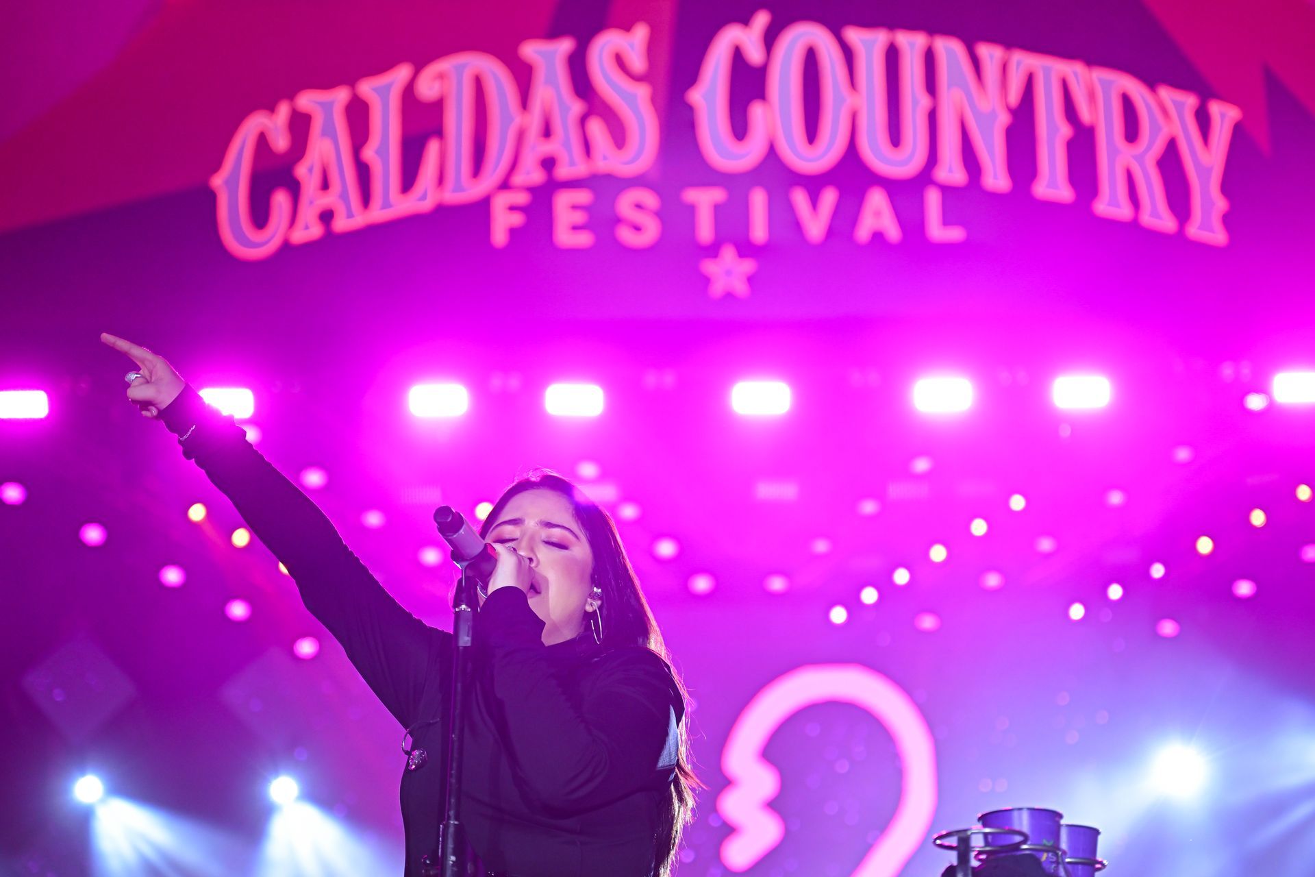 Uma mulher cantando em um microfone no festival country de caldas