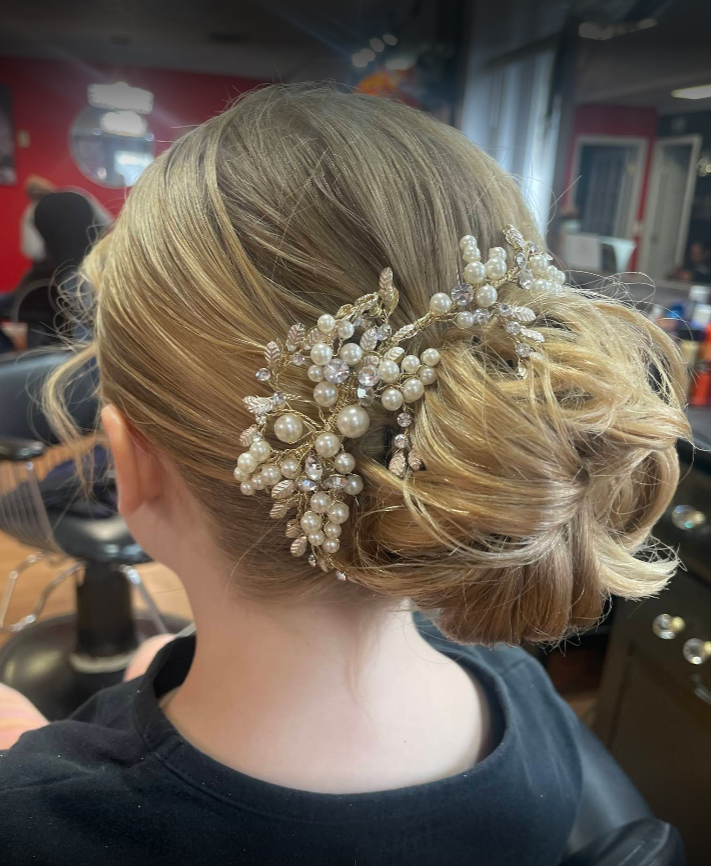 A woman is wearing a bun with pearls and rhinestones in her hair.