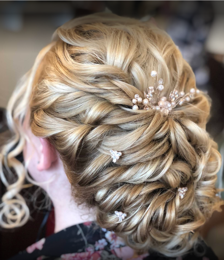 A woman with blonde hair in a bun with pearls in her hair.
