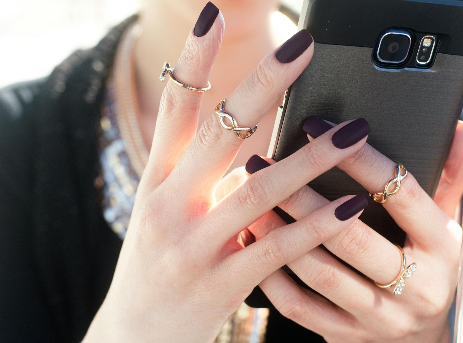 A woman with purple nails is holding a cell phone