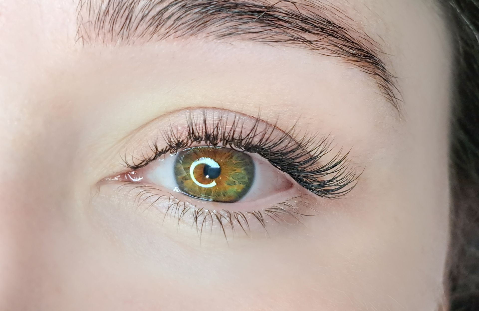 A close up of a woman 's green eye with long eyelashes.