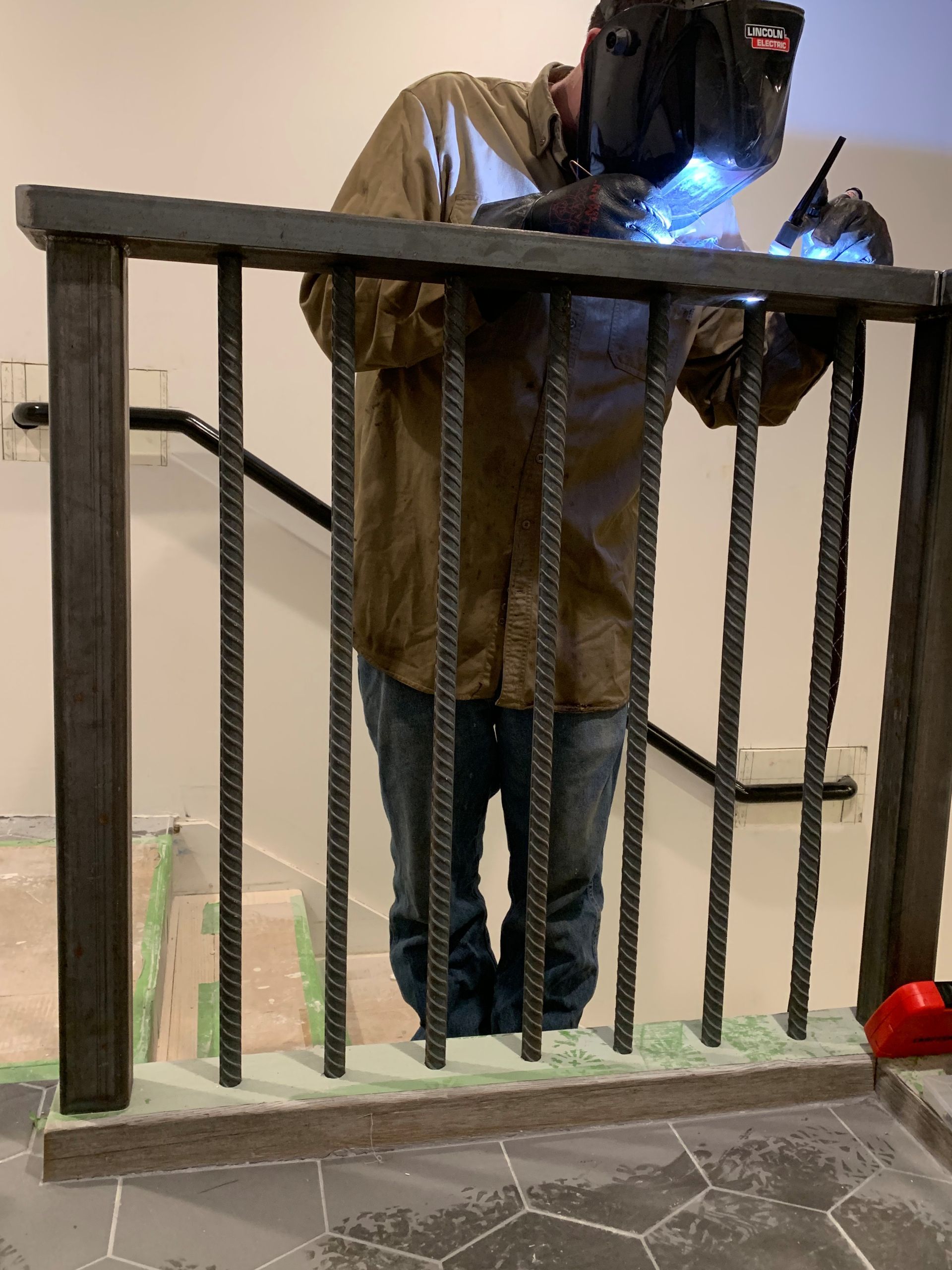 A man is welding a railing on a set of stairs.