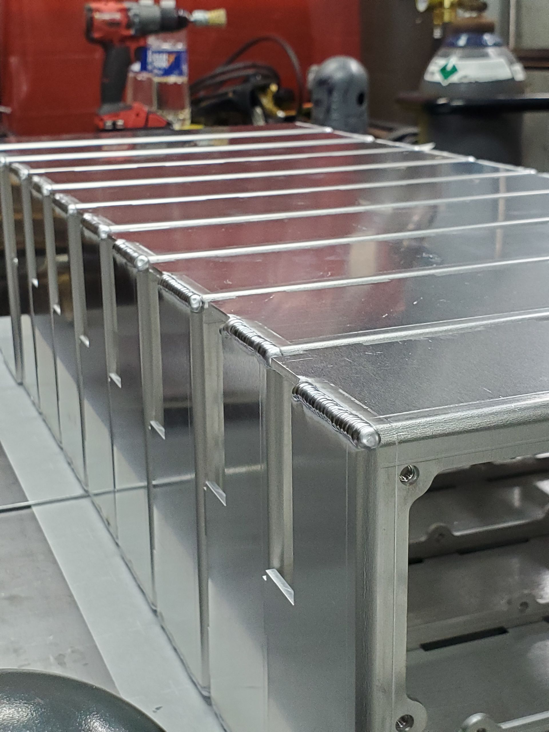 A row of aluminum boxes with a drill in the background