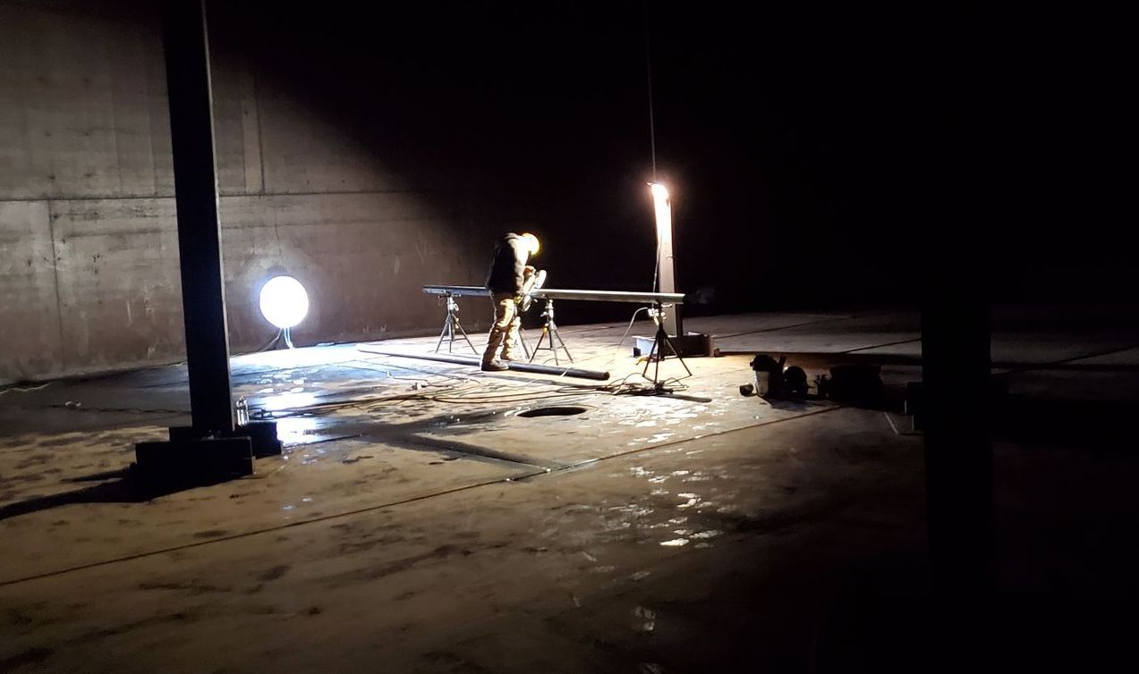 A person is standing in a dark room with a light on.