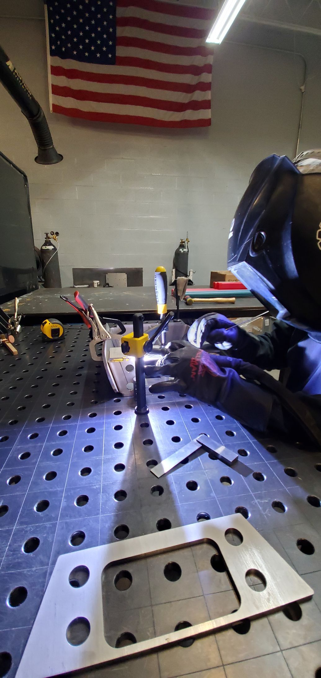 A man is welding a piece of metal on a table.