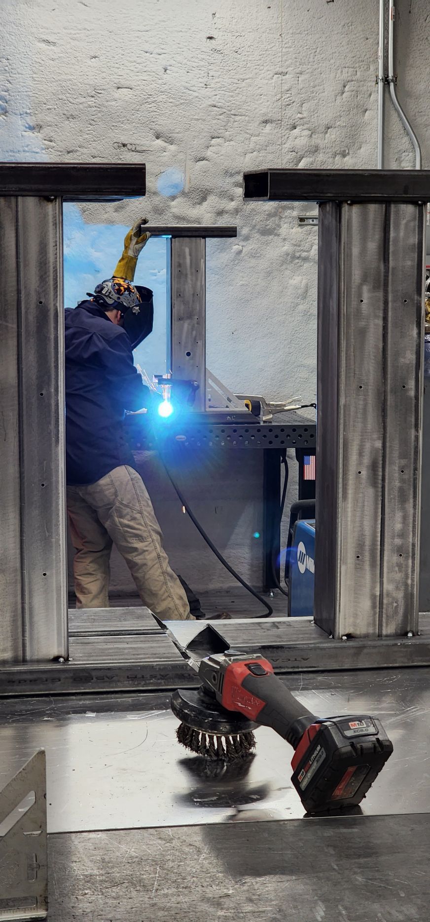 A man is welding a piece of metal in a garage.