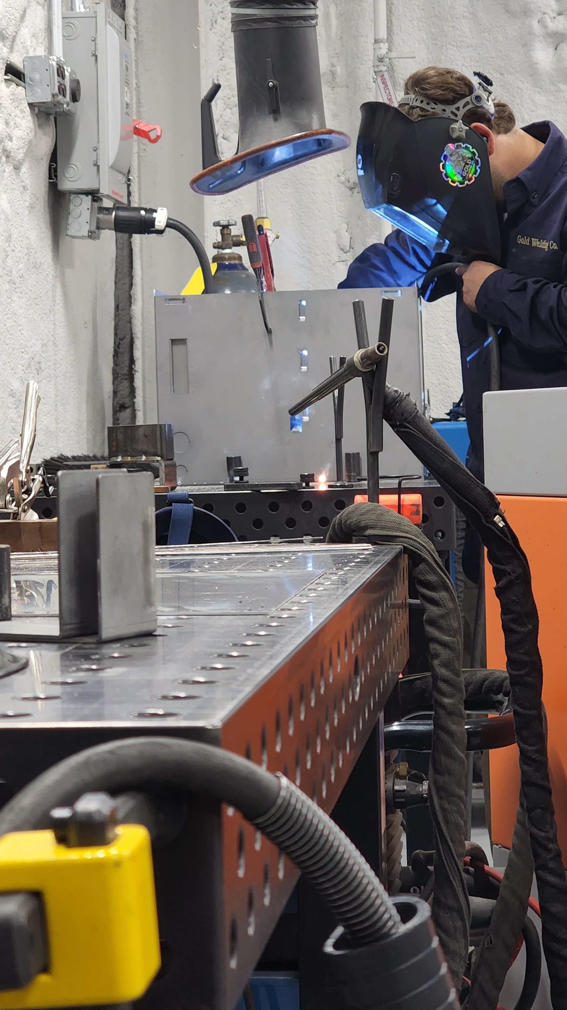 A man is welding a piece of metal in a factory.