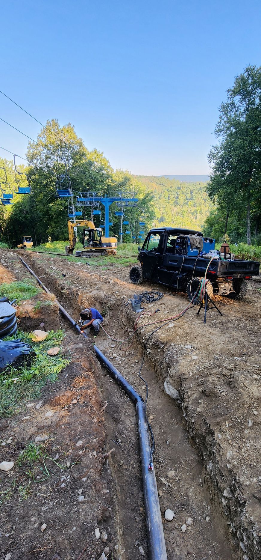 A truck is parked on the side of a dirt road next to a ski lift.