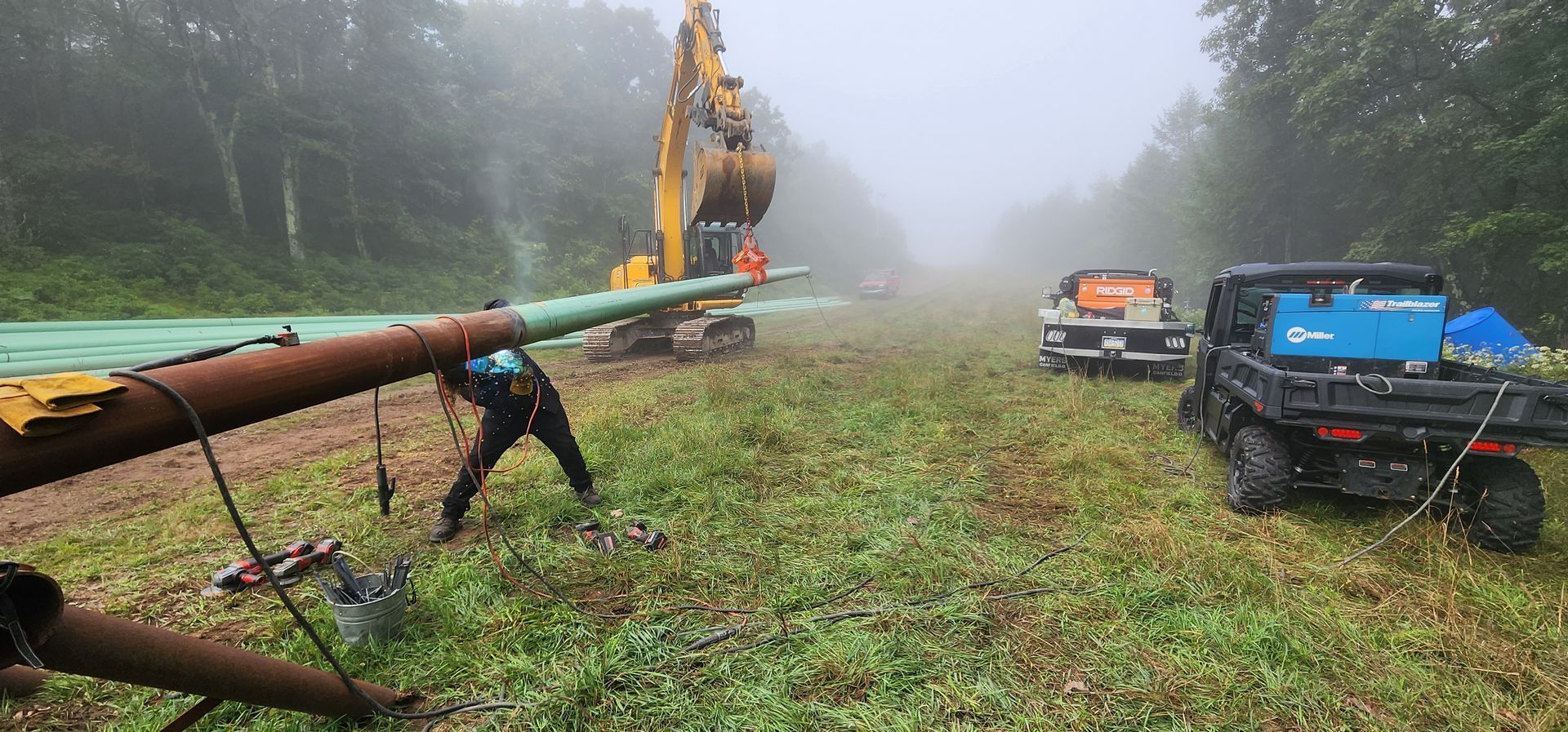 A man is working on a pipe in the middle of a field.
